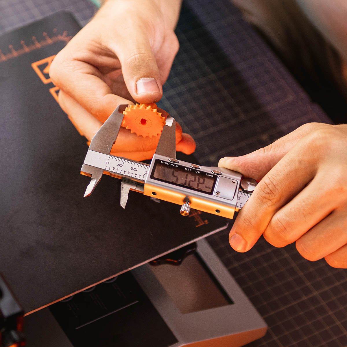 Photo of male hands measuring a 3D printed gear with digital calipers